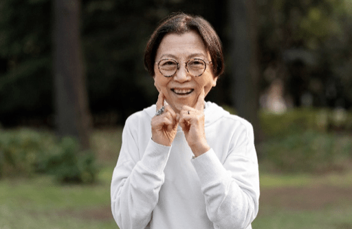Happy elderly woman wearing glasses, smiling outdoors in a park, showcasing clear vision and positive ageing.